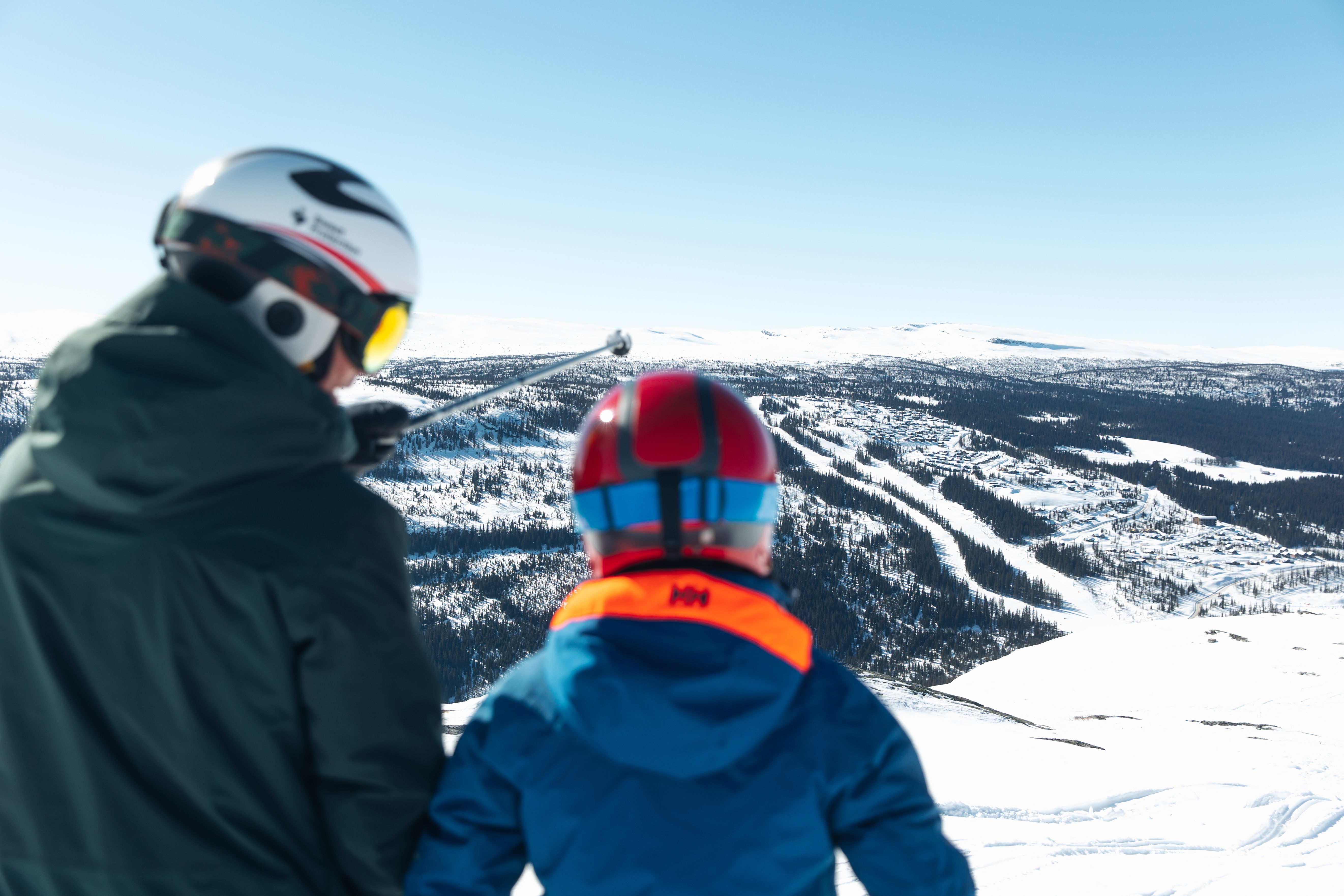 To personer på ski med utsikt over et snødekt landskap.